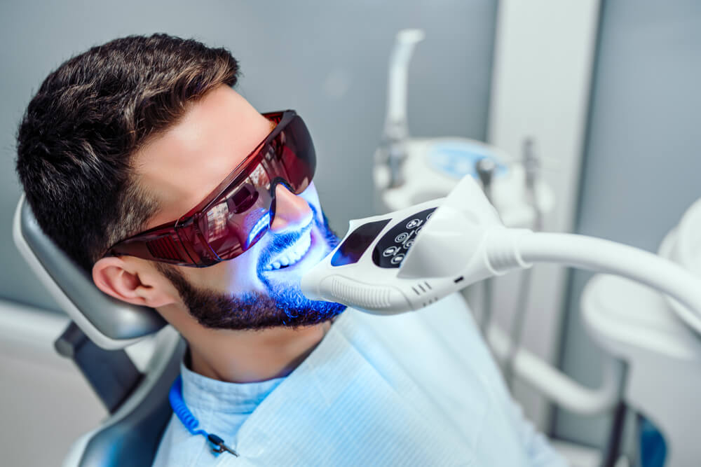 Dentist starting teeth whitening procedure