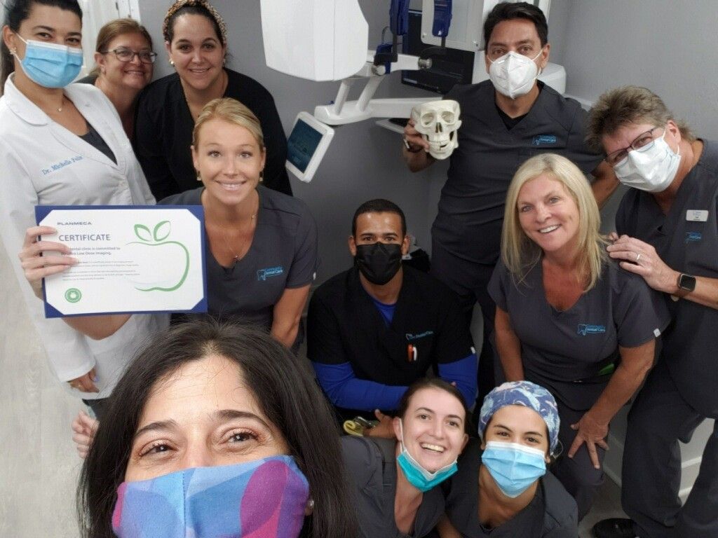 The Blue Sea Dental team posing with a certificate of excellence inside an exam room