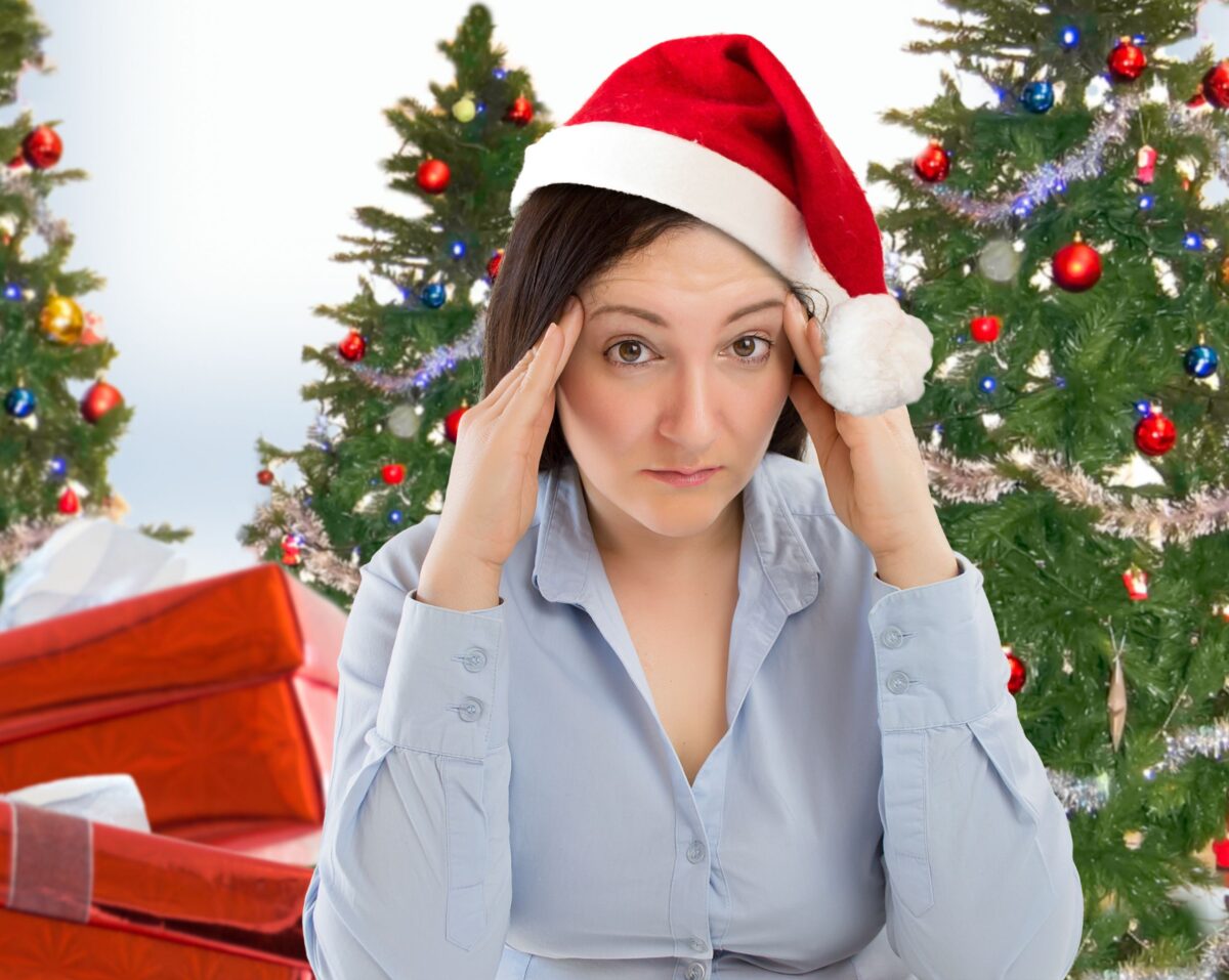 Stressed woman wearing Santa hat with Christmas trees and gifts in the background
