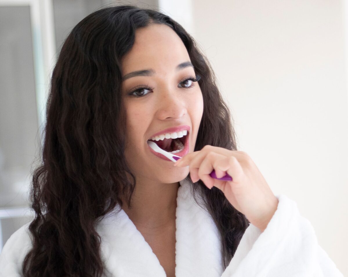 A young, dark haired woman brushing her teeth