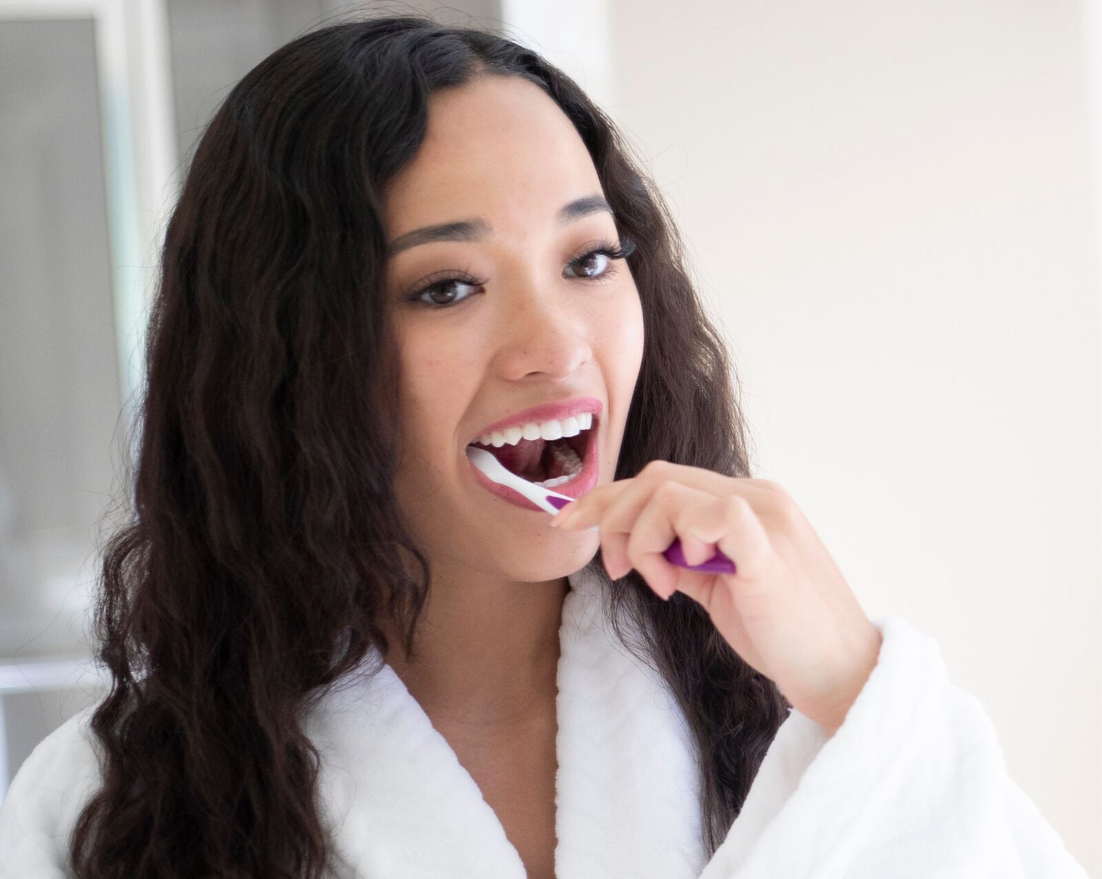 A young, dark haired woman brushing her teeth